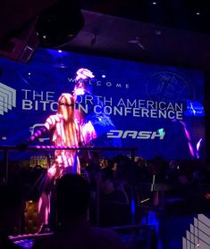 a man standing on top of a stage in front of a crowd at a convention