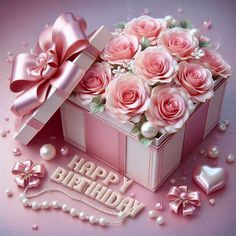 a birthday card with pink roses in a gift box and pearls on the table next to it