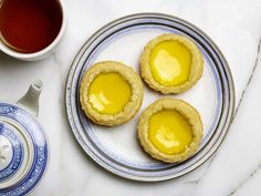 three small pastries on a plate next to a cup of tea