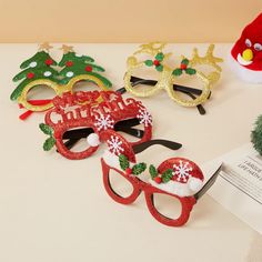 three christmas themed masks sitting on top of a table next to a santa hat and glasses