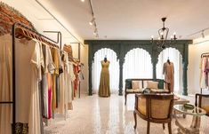 a room filled with lots of clothes on display next to a table and two chairs