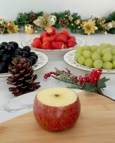 apples, grapes and pine cones are arranged on plates