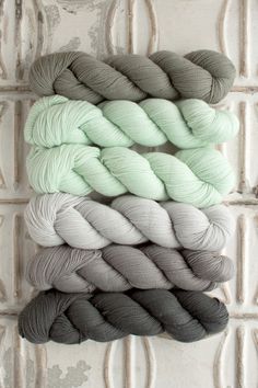 several skeins of yarn sitting on top of a white tile wall next to each other