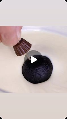 a person is spreading chocolate on top of a black object in a bowl with white liquid