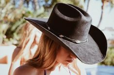 A timeless and on trend cowboy hat that’s crafted in a black faux suede with a coordinating band wrapped around. Meet the Dolly Cowboy Hat. The crown is stiffened and shaped into a clean and ridged design. Hand made by artisans, incredible quality, faux suede, lined with satin underneath. The best part? It's super structured with an elastic band on the inside that is so comfortable! No hat sizing - OSFM (one size fits most) THE HAT:-Cowboy style hat, faux suede-Stiff brim with elastic hat band o Dark Cowgirl, Yellowstone 1883, Country Festival Outfit, Country Festival, Black Hold, Black Cowboy Hat, Black Cowgirl, Suede Hat, Crown Black