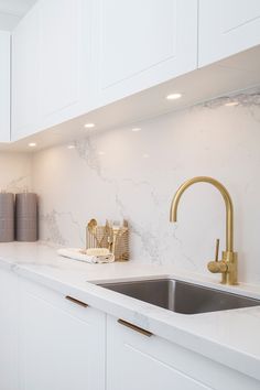 a kitchen with marble counter tops and gold faucets on the sink's side