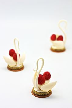 four small figurines made to look like swans with raspberries on them