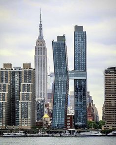 two tall buildings in the middle of a large body of water with boats passing by