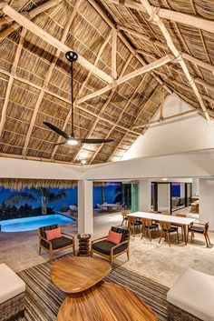 the inside of a tropical style living room with an outdoor swimming pool in the background