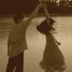 two people jumping into the air in front of water