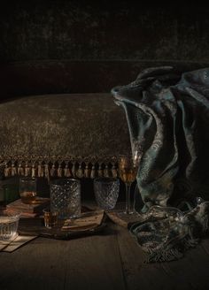 a table topped with lots of glasses next to a blanket on top of a wooden floor