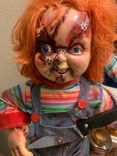 a creepy doll with red hair holding a pair of scissors in it's hands