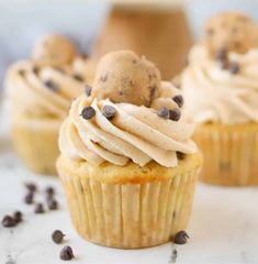 three cupcakes with frosting and chocolate chip cookies on top