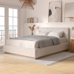 a bedroom with white walls and wood flooring has a large bed in the middle