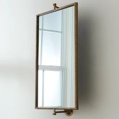 a mirror mounted to the side of a wall next to a window with no curtains