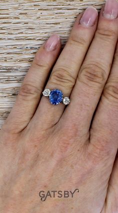 a woman's hand with an oval blue sapphire and diamond ring on top of it