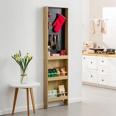 a kitchen with white walls and flooring next to a wooden shelf filled with utensils