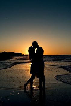 a couple kissing on the beach at sunset