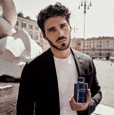 a man is holding a can of cologne in his hand and looking at the camera