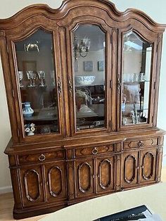 an old wooden china cabinet with glass doors and carvings on the front, in a living room