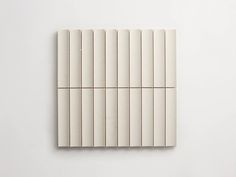 four pieces of white tile sitting on top of each other in front of a white wall