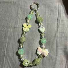 a green and white beaded bracelet with charms on it's sides, including a monkey head