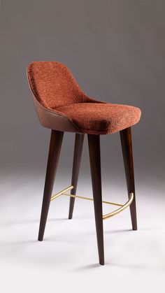 an upholstered chair with wooden legs and a red seat cover on the back