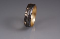 a gold and black ring with diamonds on the inside is sitting on a gray surface