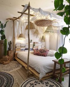 a bed with white sheets and pillows in a room next to a potted plant