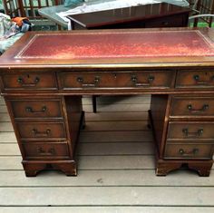 an old wooden desk with red leather top