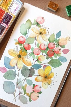 a watercolor painting of flowers and leaves on paper next to some paintbrushes