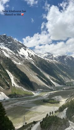 the mountains are covered in snow and green trees, with a river running through them