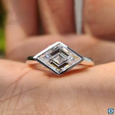 a close up of a person's hand holding a ring with a diamond in it