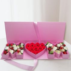 two pink boxes filled with assorted valentine's day treats on a white table