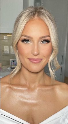 a woman with blonde hair and blue eyes wearing a white dress in a kitchen next to a sink