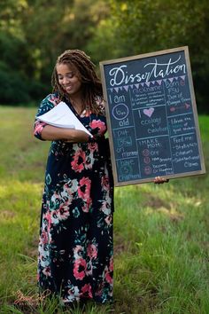 a woman standing in the grass holding a sign that says, dissection can be written on it