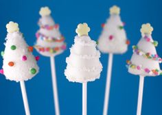 white cake pops decorated with christmas trees and sprinkles on a blue background