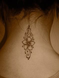 a woman's back neck with a flower tattoo on the upper part of it