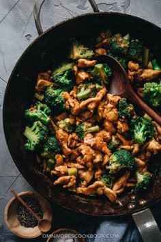 chicken and broccoli stir frying in a skillet with wooden spoons