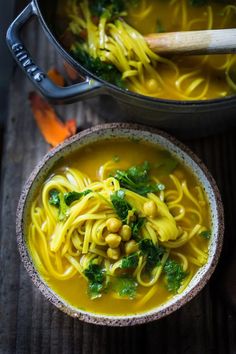 two bowls filled with noodles and vegetables on top of a wooden table