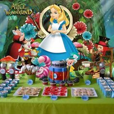 the table is set up with many items for alice's wonderland party, including candy and treats