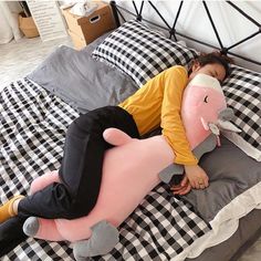 a woman laying on top of a bed with an inflatable pig pillow next to her