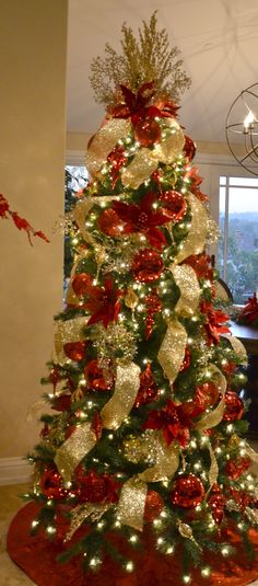 a decorated christmas tree with red and gold decorations in a living room next to a window