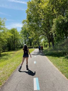 a woman rollerblading down a road with trees in the background