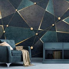 a living room with a blue couch and gold geometric wallpaper