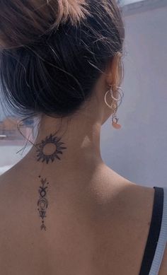 the back of a woman's neck with a sun and moon tattoo on it