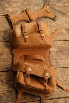 a brown leather backpack sitting on top of a wooden floor