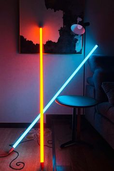 two neon lights in the corner of a room next to a chair and table with a lamp on it