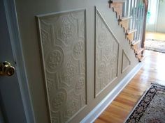 a stair case with decorative paneling on the wall and wood floors in front of it