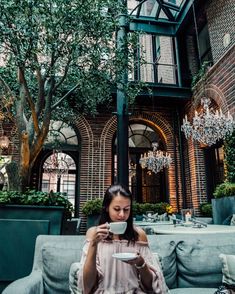 a woman sitting on a couch drinking from a cup